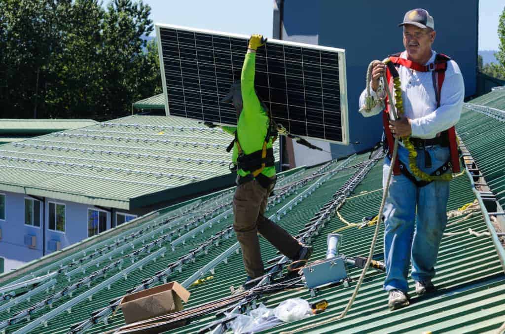 Crews move solar panels into place on the rooftop.