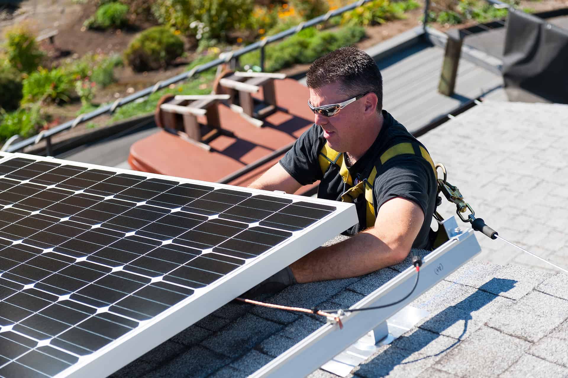 A Neil Kelly solar installer wires up solar panels on a roof