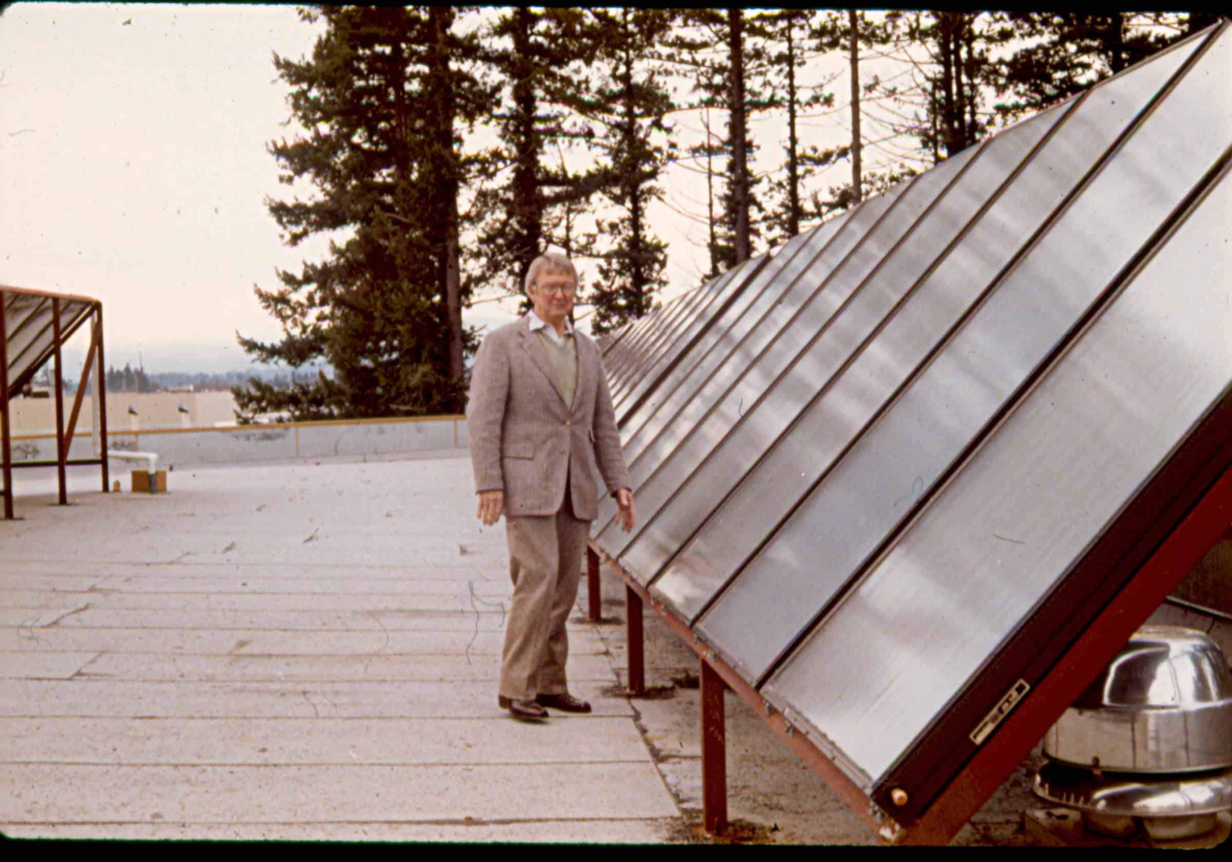 Neil B. Kelly standing next to the latest solar energy technology in the 1980s